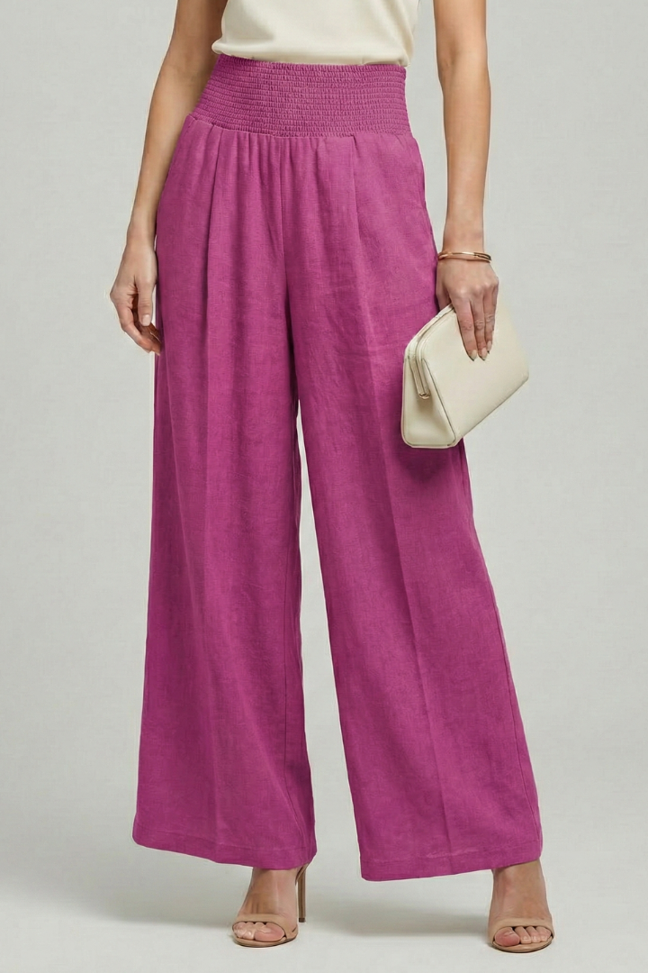 Women’s high-waist palazzo trousers with pleats by Jesie-London, featuring flowing fabric and wide-leg style.