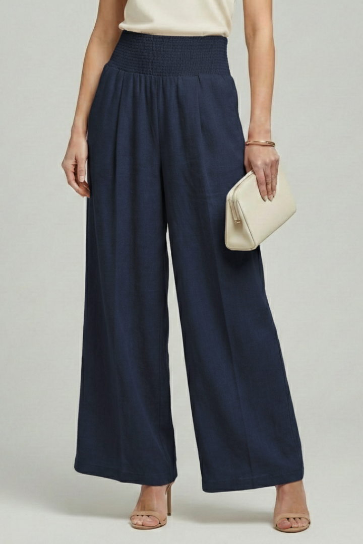 Women’s palazzo trousers by Jesie-London featuring high waist and pleats, shown on a model with a relaxed fit and elegant style.